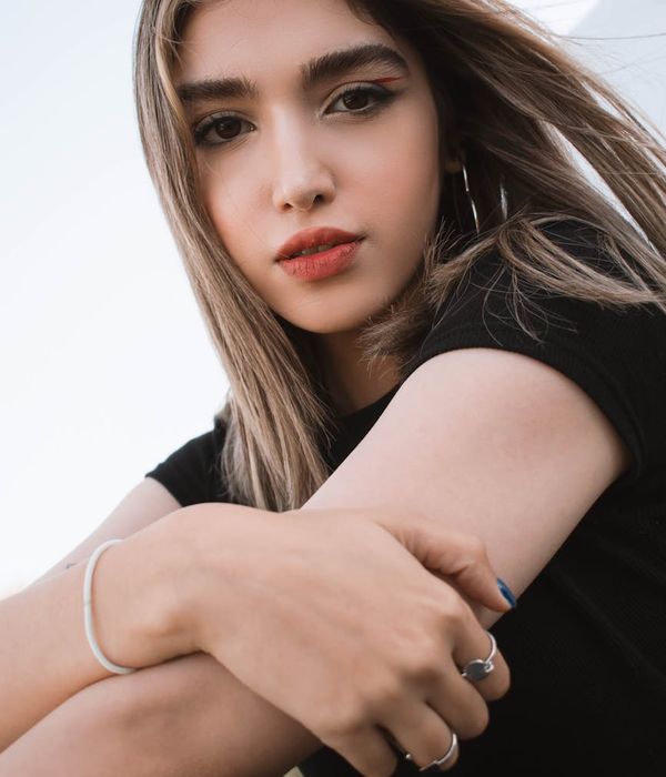 Woman in a calm yoga pose against a dark blue background.